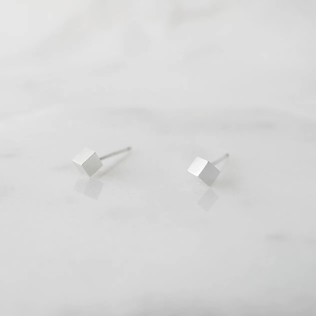 シルバー925のキューブ型スタッドピアス。ミニマルで重ね着けにも最適なデザイン。金属アレルギー対応。925 sterling silver cube stud earrings with minimalist design, perfect for layering. Hypoallergenic finish.
