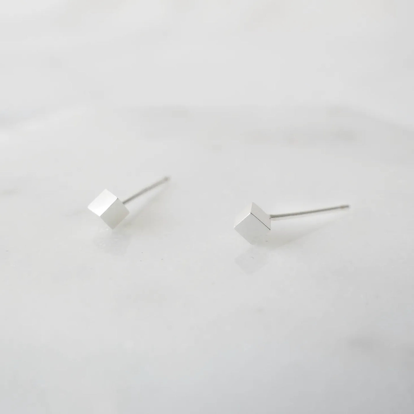 シルバー925のキューブ型スタッドピアス。ミニマルで重ね着けにも最適なデザイン。金属アレルギー対応。925 sterling silver cube stud earrings with minimalist design, perfect for layering. Hypoallergenic finish.