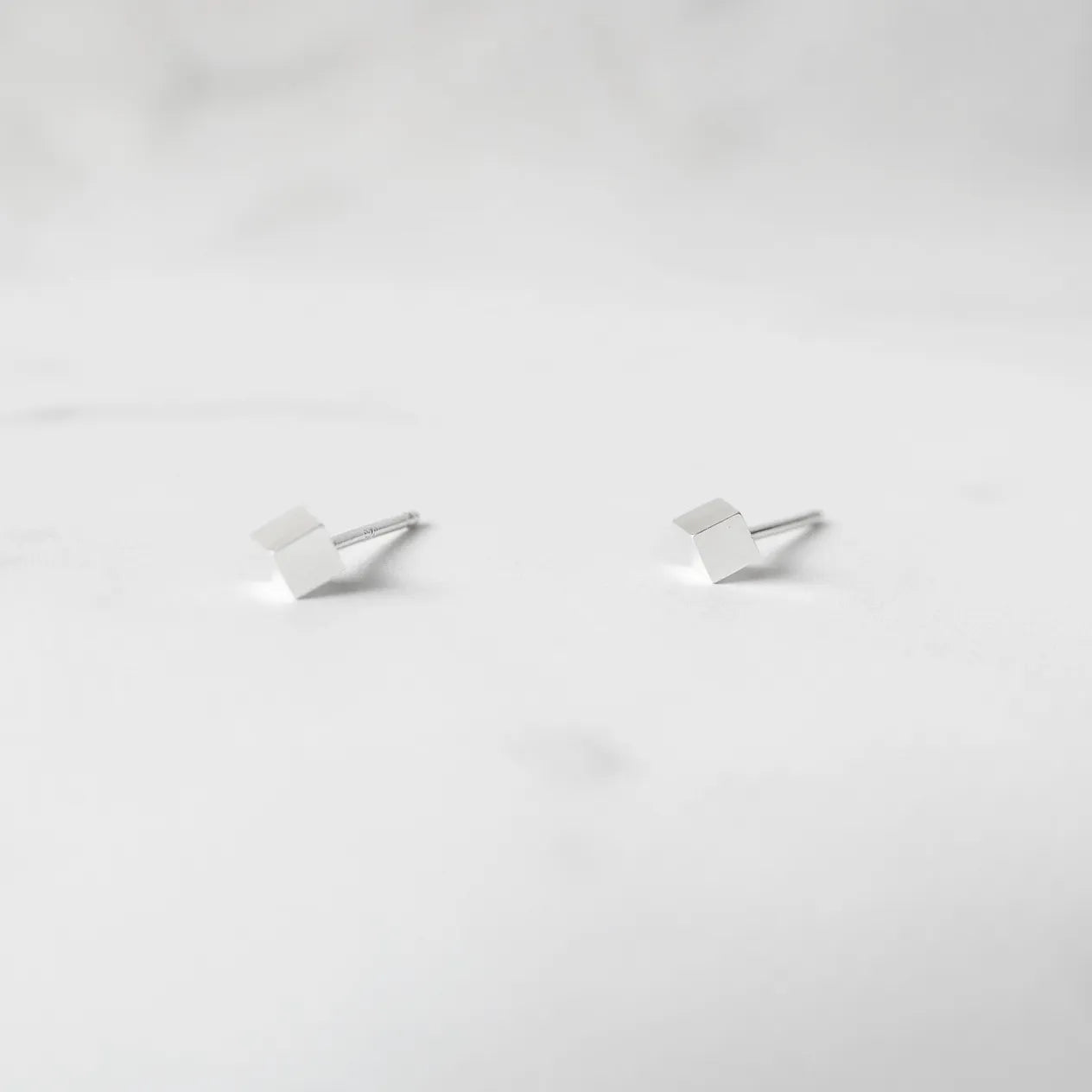 シルバー925のキューブ型スタッドピアス。ミニマルで重ね着けにも最適なデザイン。金属アレルギー対応。925 sterling silver cube stud earrings with minimalist design, perfect for layering. Hypoallergenic finish.
