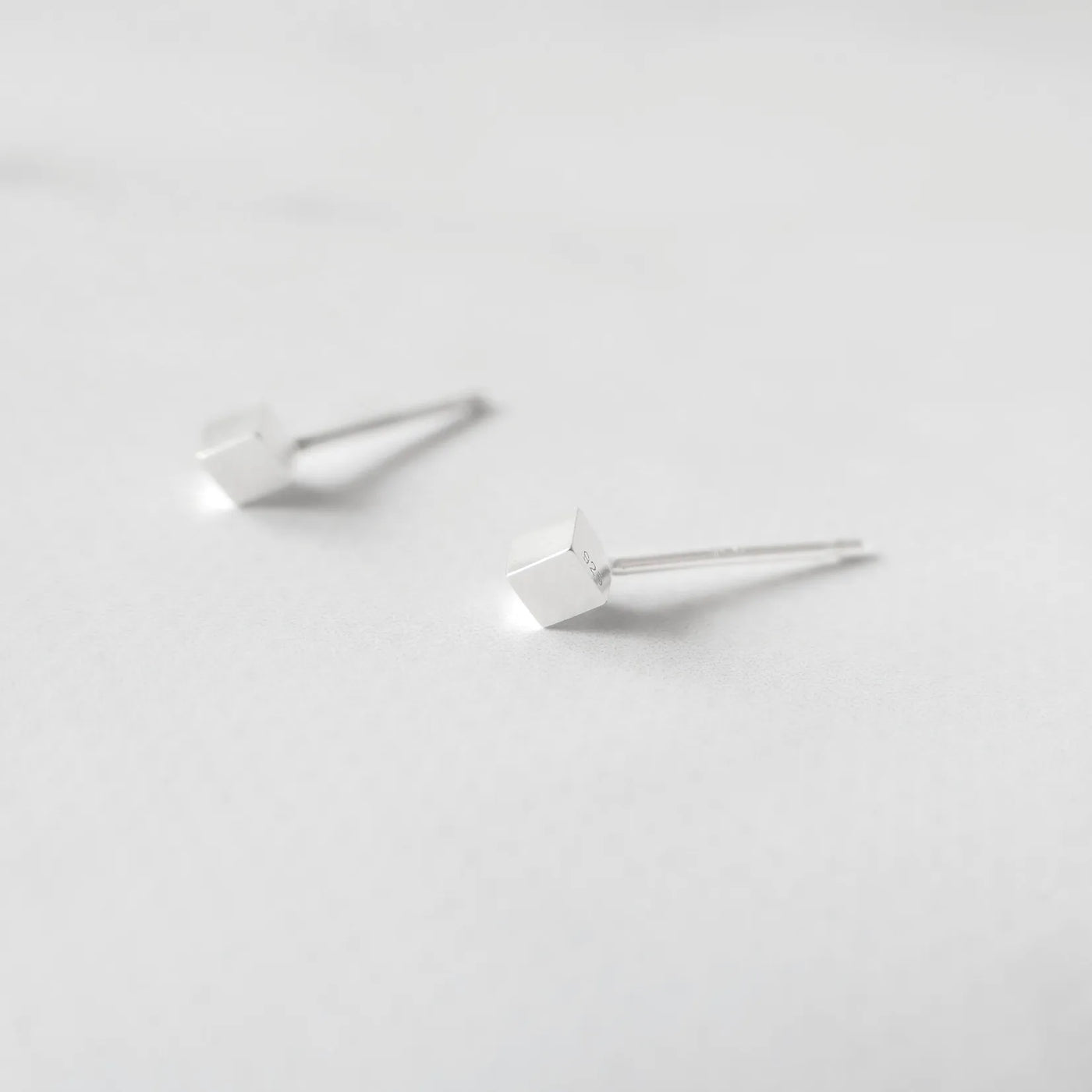 シルバー925のキューブ型スタッドピアス。ミニマルで重ね着けにも最適なデザイン。金属アレルギー対応。925 sterling silver cube stud earrings with minimalist design, perfect for layering. Hypoallergenic finish.