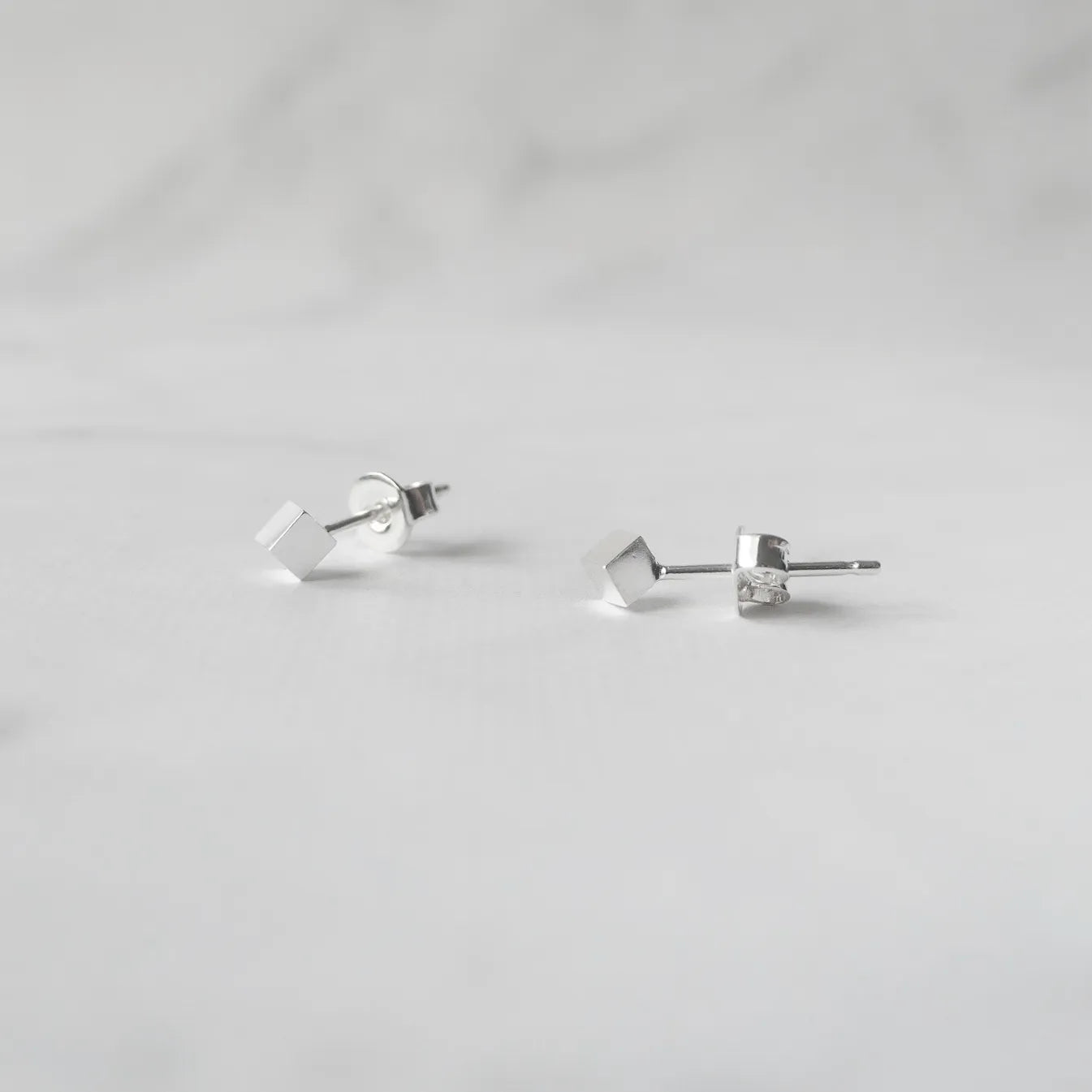 シルバー925のキューブ型スタッドピアス。ミニマルで重ね着けにも最適なデザイン。金属アレルギー対応。925 sterling silver cube stud earrings with minimalist design, perfect for layering. Hypoallergenic finish.