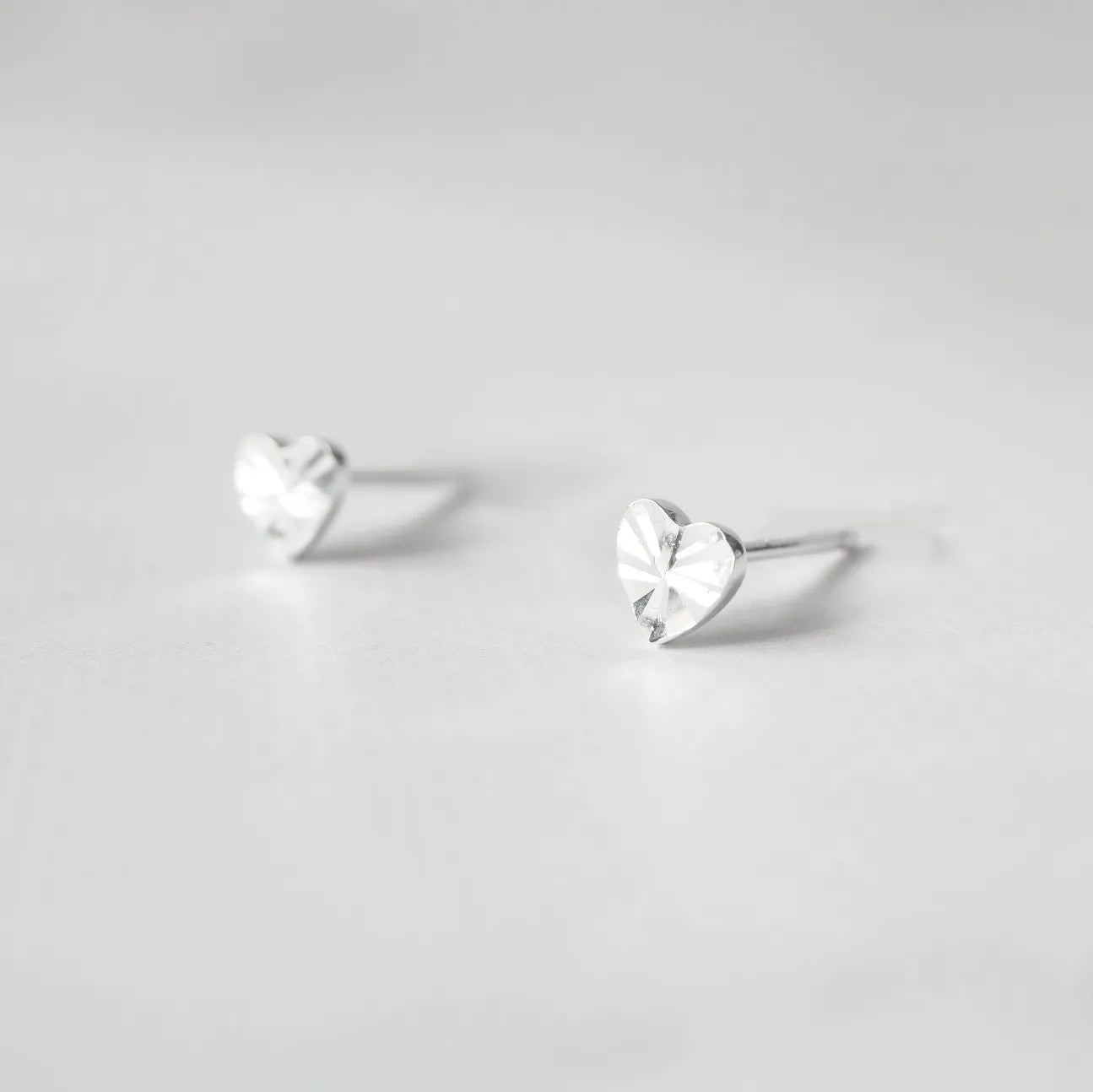 繊細なカットを施したハートモチーフのシルバー925スタッドピアス。光の反射で上品に輝くミニマルデザイン。金属アレルギー対応。
Delicately faceted heart-shaped 925 sterling silver stud earrings with a refined shine. Minimalist design, hypoallergenic.