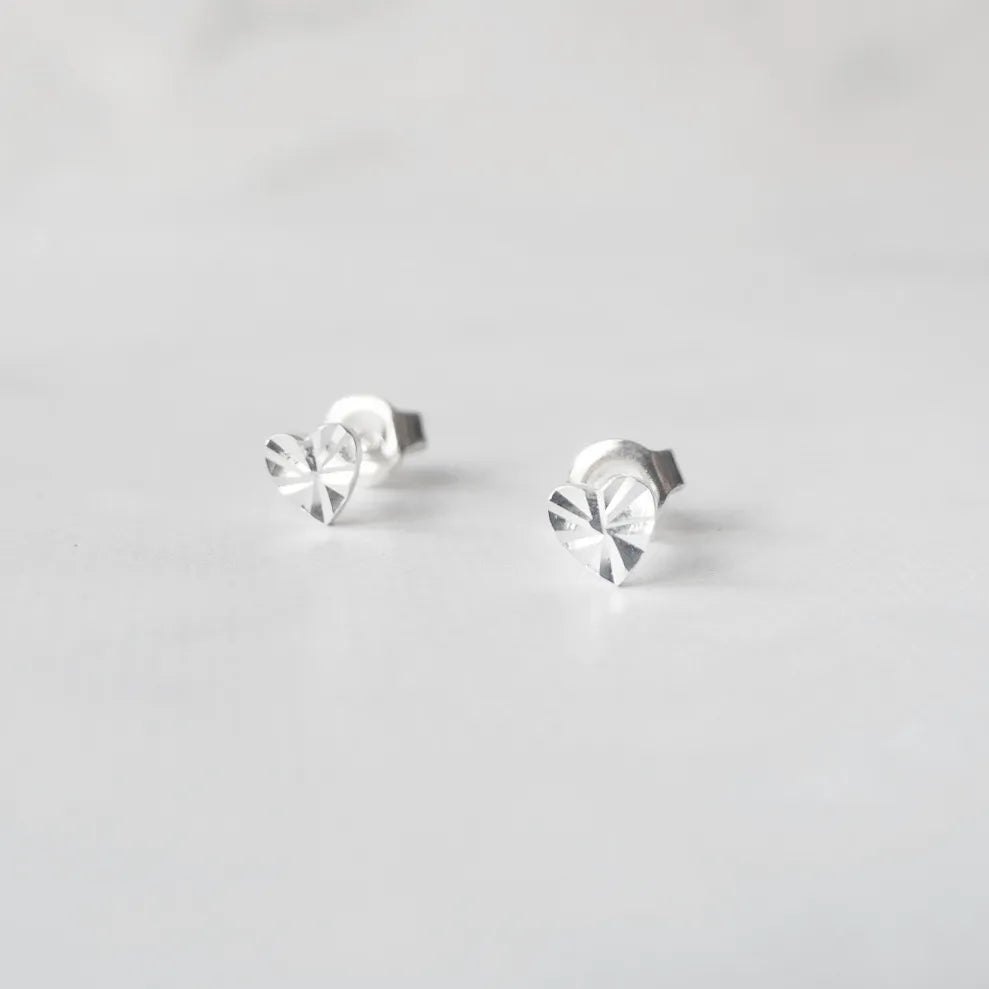 繊細なカットを施したハートモチーフのシルバー925スタッドピアス。光の反射で上品に輝くミニマルデザイン。金属アレルギー対応。
Delicately faceted heart-shaped 925 sterling silver stud earrings with a refined shine. Minimalist design, hypoallergenic.