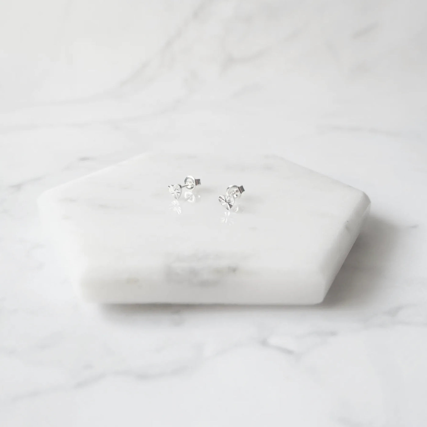 繊細なカットを施したハートモチーフのシルバー925スタッドピアス。光の反射で上品に輝くミニマルデザイン。金属アレルギー対応。
Delicately faceted heart-shaped 925 sterling silver stud earrings with a refined shine. Minimalist design, hypoallergenic.