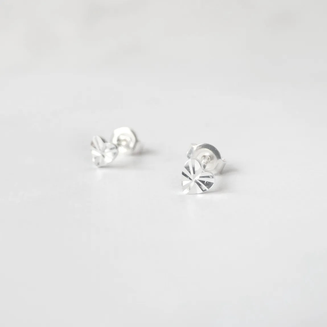 繊細なカットを施したハートモチーフのシルバー925スタッドピアス。光の反射で上品に輝くミニマルデザイン。金属アレルギー対応。
Delicately faceted heart-shaped 925 sterling silver stud earrings with a refined shine. Minimalist design, hypoallergenic.