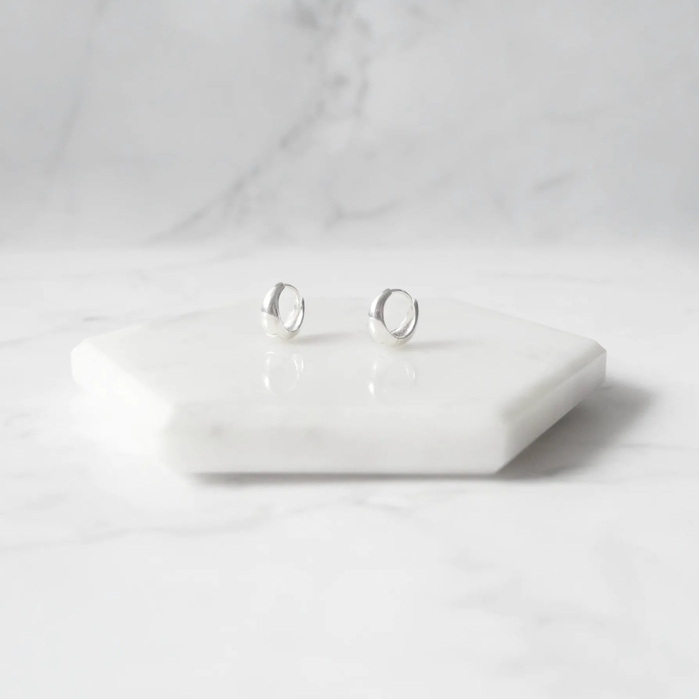 無鍍層のシルバー925を使用したクラシックハギーピアス。自然な艶感とミニマルなデザインが魅力。Classic huggie earrings in unplated 925 sterling silver with natural shine and minimalist design.