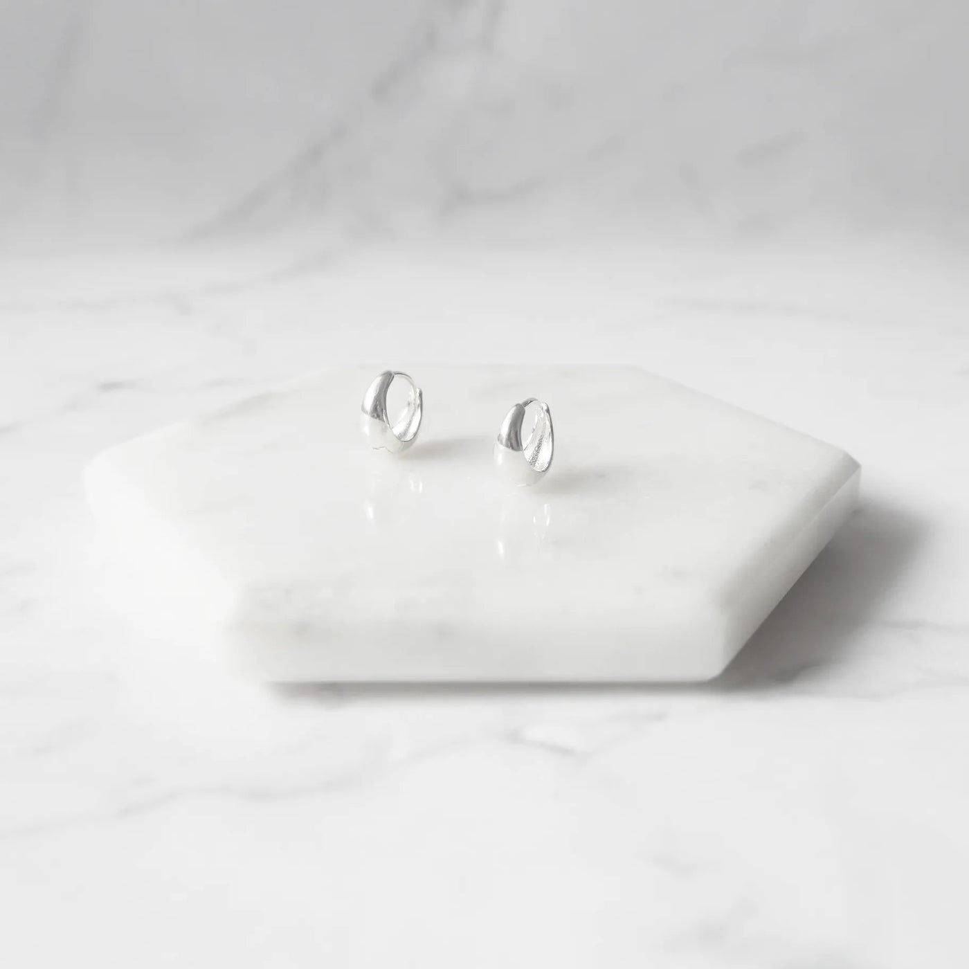 無鍍層のシルバー925を使用したクラシックハギーピアス。自然な艶感とミニマルなデザインが魅力。Classic huggie earrings in unplated 925 sterling silver with natural shine and minimalist design.
