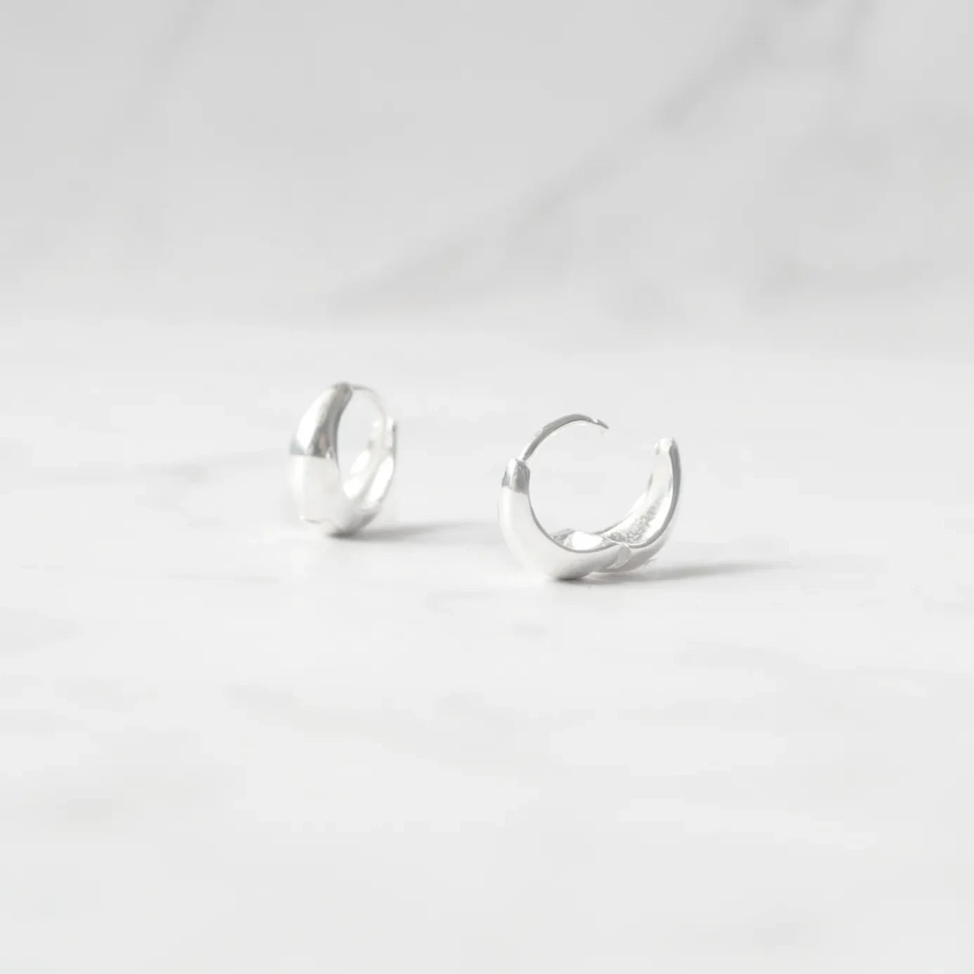 無鍍層のシルバー925を使用したクラシックハギーピアス。自然な艶感とミニマルなデザインが魅力。Classic huggie earrings in unplated 925 sterling silver with natural shine and minimalist design.