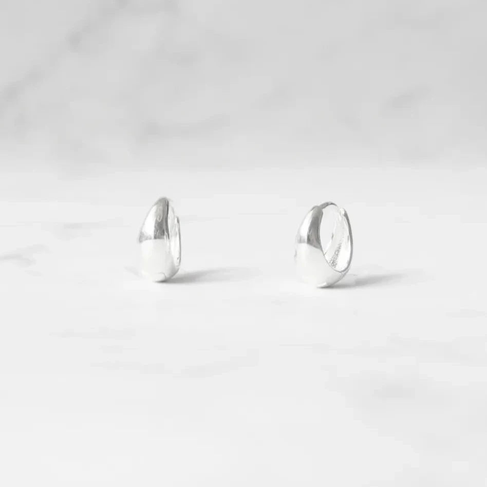 無鍍層のシルバー925を使用したクラシックハギーピアス。自然な艶感とミニマルなデザインが魅力。Classic huggie earrings in unplated 925 sterling silver with natural shine and minimalist design.