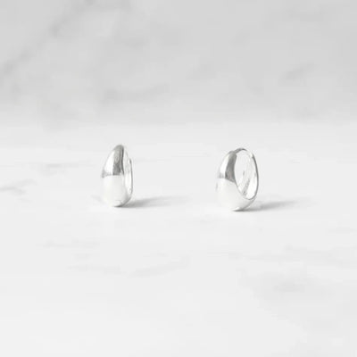 無鍍層のシルバー925を使用したクラシックハギーピアス。自然な艶感とミニマルなデザインが魅力。Classic huggie earrings in unplated 925 sterling silver with natural shine and minimalist design.
