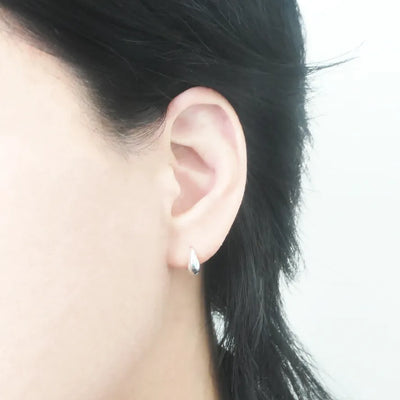 無鍍層のシルバー925を使用したクラシックハギーピアス。自然な艶感とミニマルなデザインが魅力。Classic huggie earrings in unplated 925 sterling silver with natural shine and minimalist design.