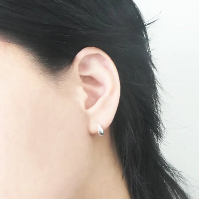 無鍍層のシルバー925を使用したクラシックハギーピアス。自然な艶感とミニマルなデザインが魅力。Classic huggie earrings in unplated 925 sterling silver with natural shine and minimalist design.