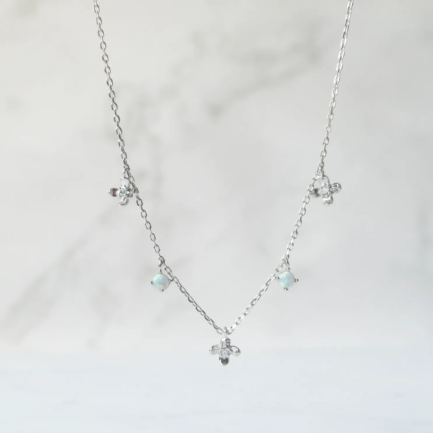 オパールとクリスタルチャームが並んだ、繊細で軽やかなシルバーネックレス。ロジウムプレーティング、金属アレルギー対応。