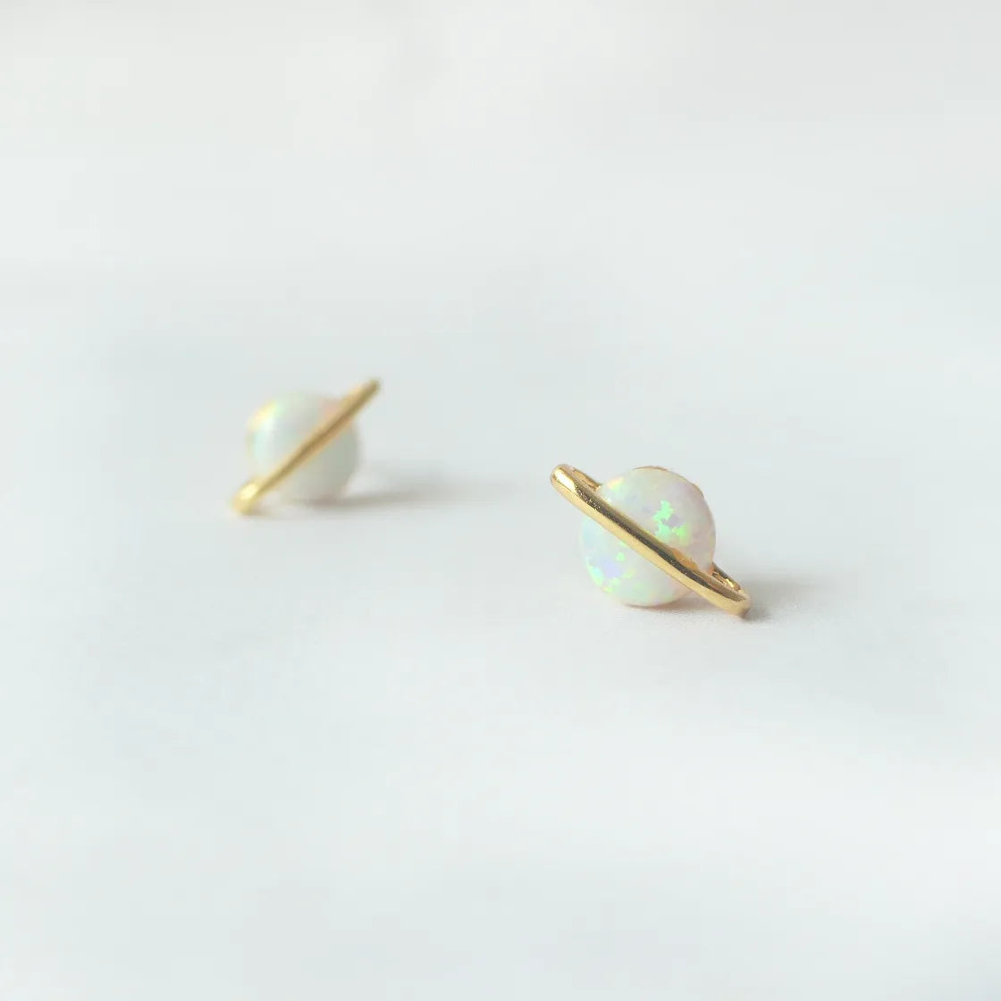 虹色の遊色を放つ天然オパールを18Kゴールドカラーのフレームに包み込んだ、惑星のように幻想的なスタッドピアス。シルバー925に18Kゴールドプレーティングを施し、耳元を柔らかく華やかに彩るデザイン。金属アレルギー対応。