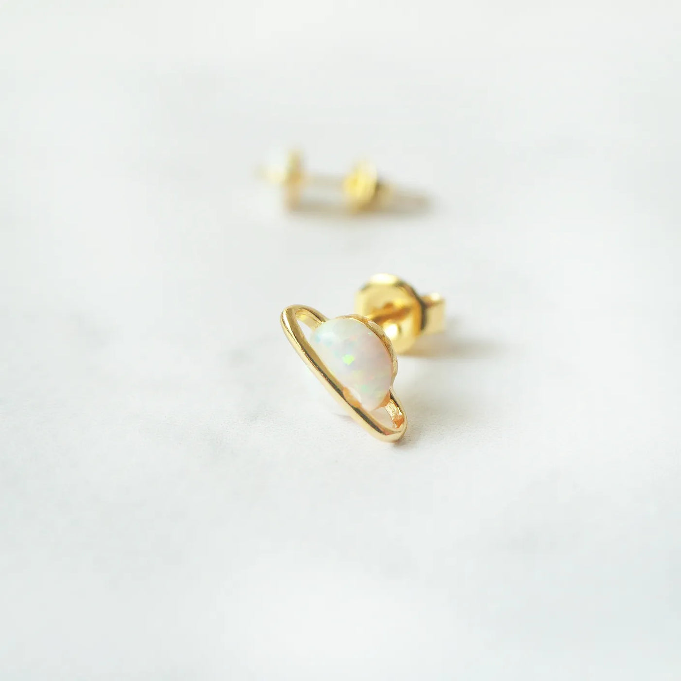 虹色の遊色を放つ天然オパールを18Kゴールドカラーのフレームに包み込んだ、惑星のように幻想的なスタッドピアス。シルバー925に18Kゴールドプレーティングを施し、耳元を柔らかく華やかに彩るデザイン。金属アレルギー対応。