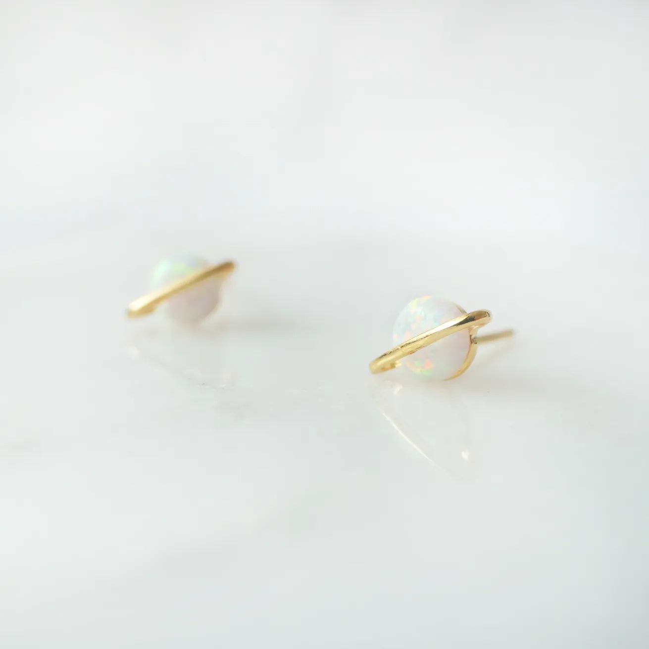 虹色の遊色を放つ天然オパールを18Kゴールドカラーのフレームに包み込んだ、惑星のように幻想的なスタッドピアス。シルバー925に18Kゴールドプレーティングを施し、耳元を柔らかく華やかに彩るデザイン。金属アレルギー対応。