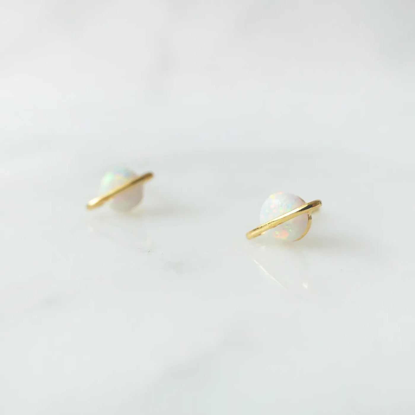 虹色の遊色を放つ天然オパールを18Kゴールドカラーのフレームに包み込んだ、惑星のように幻想的なスタッドピアス。シルバー925に18Kゴールドプレーティングを施し、耳元を柔らかく華やかに彩るデザイン。金属アレルギー対応。