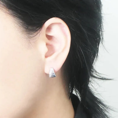 リブデザインのシルバー925ロジウムプレーティングミニフープスタッドピアス。鏡面仕上げで立体感ある輝き、金属アレルギー対応。
Ribbed design mini hoop stud earrings in 925 sterling silver, rhodium plated. Mirror-finish shine with dimensional style, hypoallergenic.