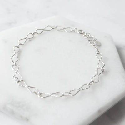 くり抜きのリボンモチーフと刻み模様が施されたチェーンブレスレット。シルバー925素材・金属アレルギー対応。