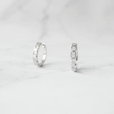 スクエアカットのジルコニアを並べたシルバー925ロジウムプレーティングフープピアス。モダンで上品な輝き、金属アレルギー対応。
Hoop earrings with square-cut zirconia in 925 sterling silver, rhodium plated. Modern, elegant sparkle, hypoallergenic.