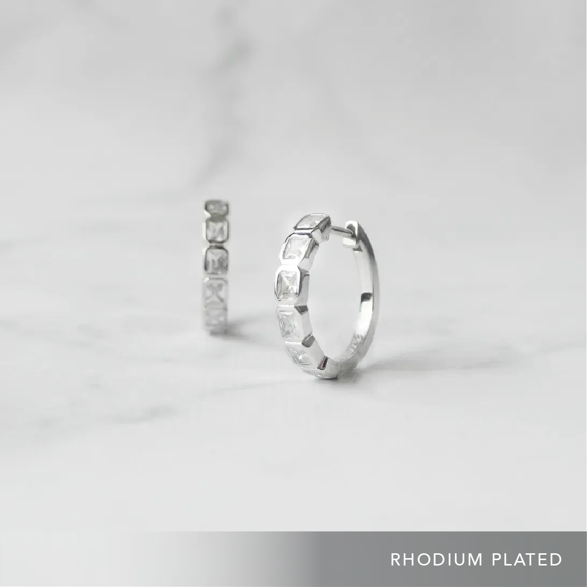 スクエアカットのジルコニアを並べたシルバー925ロジウムプレーティングフープピアス。モダンで上品な輝き、金属アレルギー対応。
Hoop earrings with square-cut zirconia in 925 sterling silver, rhodium plated. Modern, elegant sparkle, hypoallergenic.
