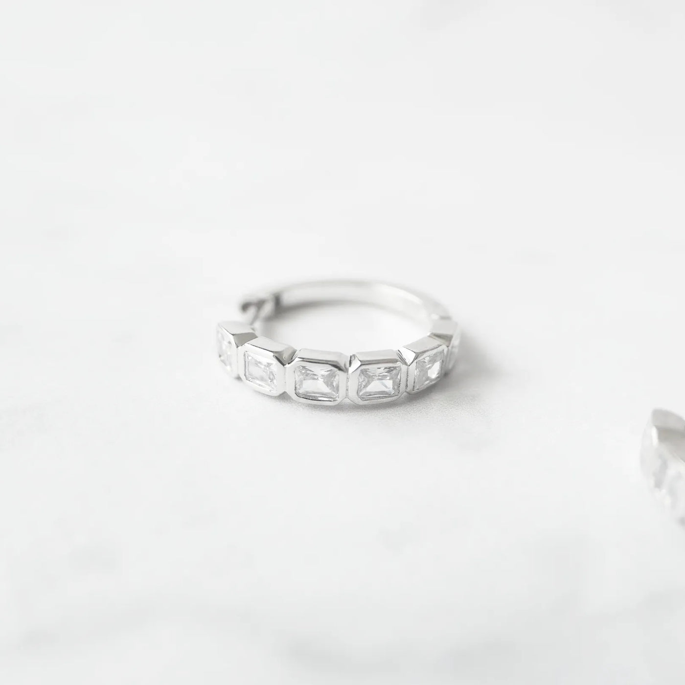 スクエアカットのジルコニアを並べたシルバー925ロジウムプレーティングフープピアス。モダンで上品な輝き、金属アレルギー対応。
Hoop earrings with square-cut zirconia in 925 sterling silver, rhodium plated. Modern, elegant sparkle, hypoallergenic.