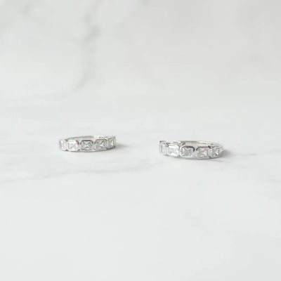 スクエアカットのジルコニアを並べたシルバー925ロジウムプレーティングフープピアス。モダンで上品な輝き、金属アレルギー対応。
Hoop earrings with square-cut zirconia in 925 sterling silver, rhodium plated. Modern, elegant sparkle, hypoallergenic.