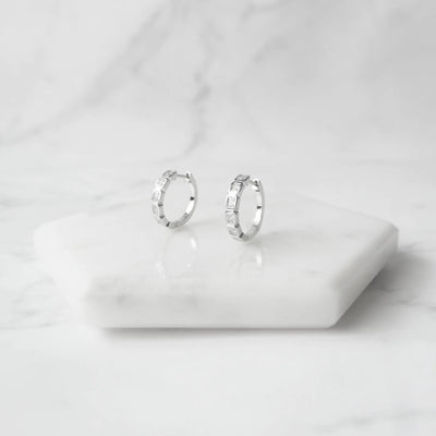 スクエアカットのジルコニアを並べたシルバー925ロジウムプレーティングフープピアス。モダンで上品な輝き、金属アレルギー対応。
Hoop earrings with square-cut zirconia in 925 sterling silver, rhodium plated. Modern, elegant sparkle, hypoallergenic.