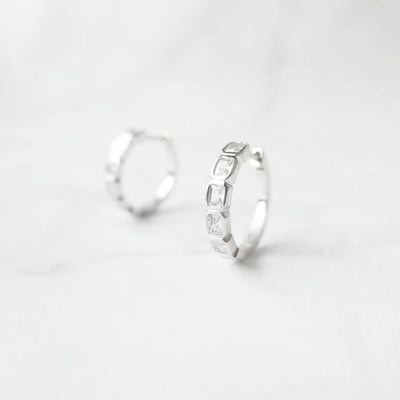 スクエアカットのジルコニアを並べたシルバー925ロジウムプレーティングフープピアス。モダンで上品な輝き、金属アレルギー対応。
Hoop earrings with square-cut zirconia in 925 sterling silver, rhodium plated. Modern, elegant sparkle, hypoallergenic.